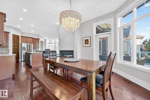Dining room with dark wood-style floors, recessed lighting, a glass covered fireplace, and a chandelier - 940 Haliburton Road, Edmonton, AB - Indoor Photo Showing Dining Room