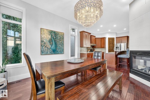 Dining space with dark wood-type flooring, a fireplace, plenty of natural light, a chandelier, and recessed lighting - 940 Haliburton Road, Edmonton, AB - Indoor Photo Showing Dining Room With Fireplace