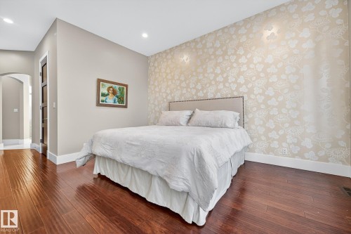 Bedroom featuring arched walkways, wallpapered walls, dark wood-style flooring, an accent wall, and recessed lighting - 940 Haliburton Road, Edmonton, AB - Indoor Photo Showing Bedroom