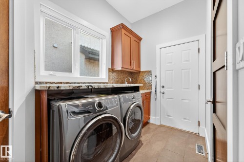 Washroom featuring washer and dryer, cabinet space, and light tile patterned floors - 940 Haliburton Road, Edmonton, AB - Indoor Photo Showing Laundry Room