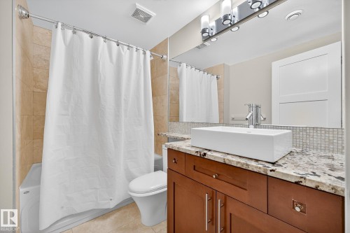 Full bathroom featuring shower / bath combo with shower curtain, vanity, backsplash, and light tile patterned floors - 940 Haliburton Road, Edmonton, AB - Indoor Photo Showing Bathroom