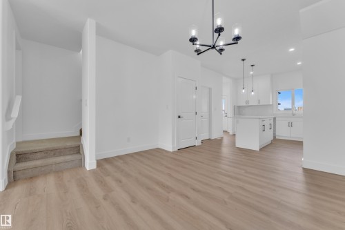 Open-concept living area featuring wood-finish flooring, a modern black chandelier, and recessed lighting - 285 Munn Way, Leduc, AB - Indoor Photo Showing Kitchen