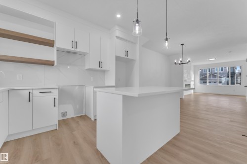 Kitchen featuring a white island with countertop, white cabinetry with matte black hardware, wood-finish open shelving, and a tiled backsplash - 285 Munn Way, Leduc, AB - Indoor Photo Showing Kitchen With Upgraded Kitchen