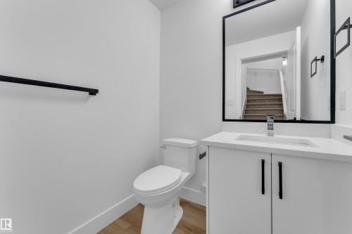 Bathroom featuring a white vanity with a light-toned countertop, a rectangular sink with a chrome faucet, and a large mirror with a black frame - 285 Munn Way, Leduc, AB - Indoor Photo Showing Bathroom