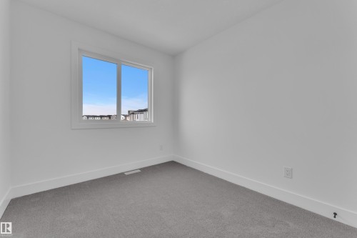 Bright room featuring a large window with white trim, plush gray carpeting, and clean white walls - 285 Munn Way, Leduc, AB - Indoor Photo Showing Other Room