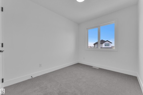 Bright interior room featuring a large window, light gray carpet, white walls, and white trim - 285 Munn Way, Leduc, AB - Indoor Photo Showing Other Room