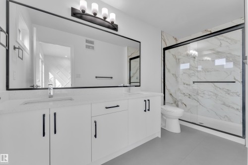Modern bathroom featuring a dual vanity with white cabinetry, integrated sinks, and light-toned countertops - 285 Munn Way, Leduc, AB - Indoor Photo Showing Bathroom