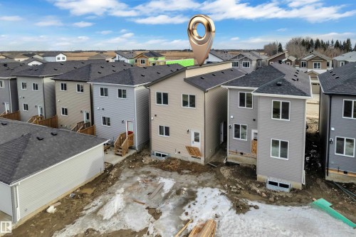 Contemporary two-story residence with light beige siding, multiple windows, and a dark shingle roof - 285 Munn Way, Leduc, AB - Outdoor