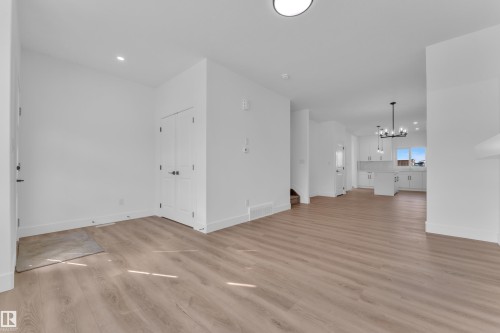 Spacious interior featuring wood-finish flooring, white walls, and a modern chandelier - 285 Munn Way, Leduc, AB - Indoor Photo Showing Other Room