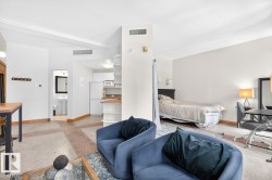Open-concept living area featuring a neutral color palette, wood-finish baseboards, and a combination of carpet and hard-surface flooring - 