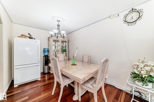 This room features rich hardwood flooring, a chandelier with decorative ceiling medallion, and a built-in display cabinet - 8733 181A Street Nw, Edmonton, AB - Indoor Photo Showing Dining Room