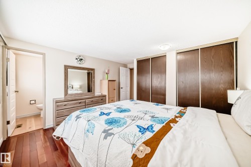 The property features rich hardwood flooring, a spacious bedroom with ample closet space, and a private attached bathroom - 8733 181A Street Nw, Edmonton, AB - Indoor Photo Showing Bedroom