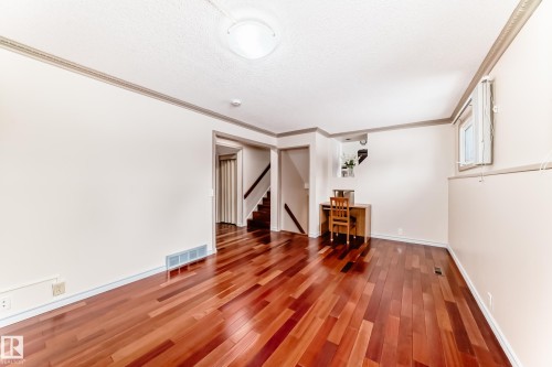 Spacious room featuring rich hardwood flooring, light-colored walls, and decorative ceiling trim - 8733 181A Street Nw, Edmonton, AB - Indoor Photo Showing Other Room