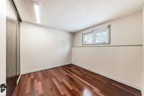 This room features rich hardwood flooring, a bright window, and a sliding closet door - 8733 181A Street Nw, Edmonton, AB - Indoor Photo Showing Other Room