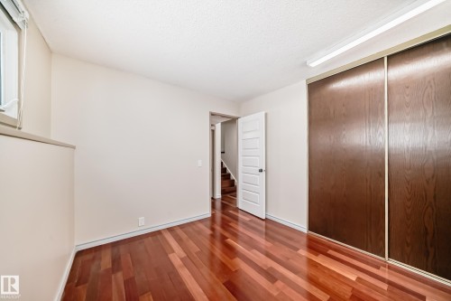 Room featuring polished hardwood floors and a built-in closet with sliding doors - 8733 181A Street Nw, Edmonton, AB - Indoor Photo Showing Other Room