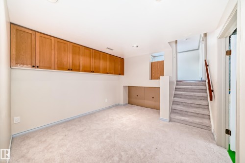 This versatile space features carpeting, recessed lighting, and extensive wood cabinetry providing ample storage - 8733 181A Street Nw, Edmonton, AB - Indoor Photo Showing Other Room