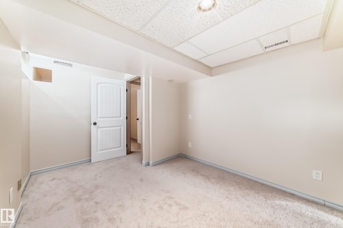 This room features neutral-toned walls, a drop ceiling with recessed lighting, and light-colored carpet flooring - 8733 181A Street Nw, Edmonton, AB - Indoor Photo Showing Other Room