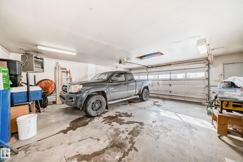 The property features a spacious garage with a concrete floor and a large garage door - 8733 181A Street Nw, Edmonton, AB - Indoor Photo Showing Garage