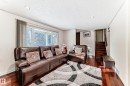 The living area features polished wood flooring, a large window, recessed lighting, and a staircase with wood treads and a dark handrail - 8733 181A Street Nw, Edmonton, AB  - Indoor Photo Showing Living Room 