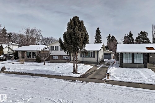 The property features a snow-covered exterior with a driveway and a large front yard - 8733 181A Street Nw, Edmonton, AB - Outdoor With Facade
