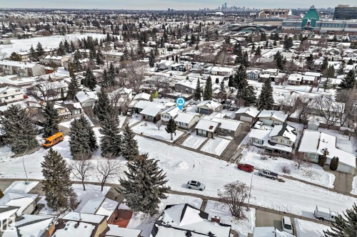 Aerial view of the property and surrounding neighborhood, featuring residential homes with snow-covered roofs and mature evergreen trees - 8733 181A Street Nw, Edmonton, AB - Outdoor With View