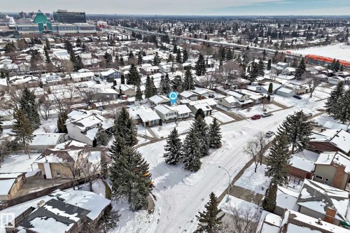 Aerial view of the property in a residential neighborhood with snow-covered roofs and mature evergreen trees - 8733 181A Street Nw, Edmonton, AB - Outdoor With View