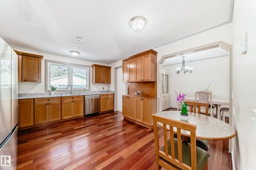 The kitchen features hardwood floors, wooden cabinetry, and stainless steel appliances - 8733 181A Street Nw, Edmonton, AB - Indoor