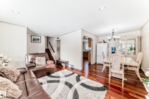 The property features lustrous hardwood flooring throughout the main living areas, complemented by recessed lighting and a classic chandelier in the dining area - 8733 181A Street Nw, Edmonton, AB - Indoor Photo Showing Living Room