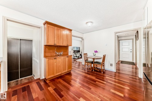This interior space features rich hardwood flooring, a built-in wooden cabinet with ample storage, and a small dining area with a round table and two chairs - 8733 181A Street Nw, Edmonton, AB - Indoor
