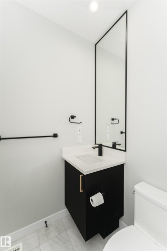 Powder room featuring a modern black vanity with a white countertop, an integrated rectangular sink, and matte black fixtures - 5386 Kimball Place, Edmonton, AB - Indoor Photo Showing Bathroom