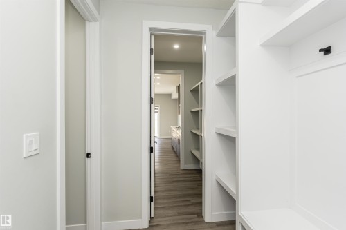 Built-in white shelving providing storage solutions, wood-finish flooring, and light gray wall paint - 5386 Kimball Place, Edmonton, AB - Indoor