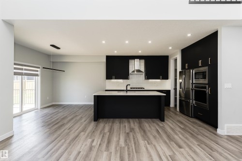 Modern kitchen featuring dark cabinetry, light countertops, and stainless steel appliances - 5386 Kimball Place, Edmonton, AB - Indoor Photo Showing Other Room