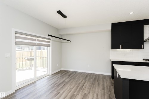 Open-concept dining area featuring wood-finish flooring and a contemporary linear pendant light - 5386 Kimball Place, Edmonton, AB - Indoor