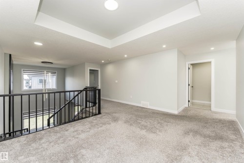 Carpeted landing featuring a coffered ceiling with recessed lighting, black metal railing, and a window with blinds - 5386 Kimball Place, Edmonton, AB - Indoor Photo Showing Other Room