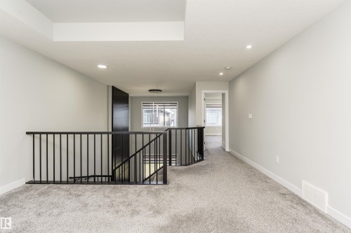 Carpeted landing with black metal railings, white baseboards, and recessed lighting - 5386 Kimball Place, Edmonton, AB - Indoor Photo Showing Other Room