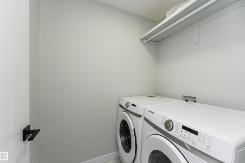 Dedicated laundry space featuring a white shelf with hanging rod, light-colored walls, and a white door with a black handle - 5386 Kimball Place, Edmonton, AB - Indoor Photo Showing Laundry Room