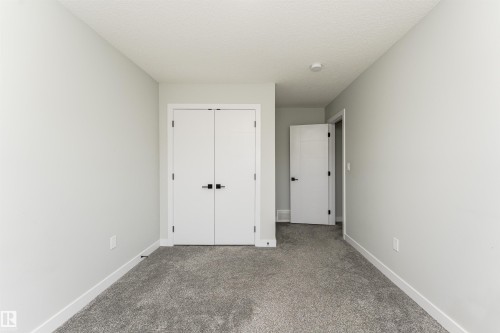 Room featuring light gray wall paint, white trim, gray carpet flooring, and two white interior doors with black hardware - 5386 Kimball Place, Edmonton, AB - Indoor Photo Showing Other Room