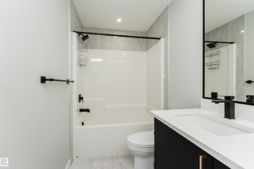 Contemporary bathroom featuring a white tub/shower combination with matte black fixtures, a floating vanity with a white countertop, and a large framed mirror - 5386 Kimball Place, Edmonton, AB - Indoor Photo Showing Bathroom