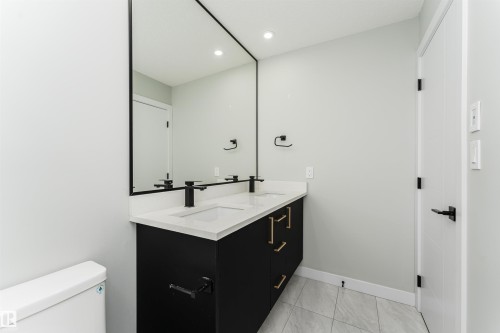 Dual vanity with dark cabinetry, gold-tone hardware, and integrated sinks - 5386 Kimball Place, Edmonton, AB - Indoor Photo Showing Bathroom