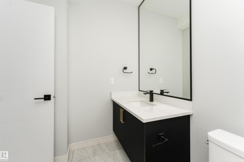 Modern vanity featuring a white countertop with integrated sink, matte black faucet, and a large black-framed mirror - 5386 Kimball Place, Edmonton, AB - Indoor Photo Showing Bathroom