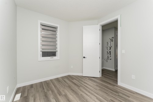 Neutral wall paint with white trim, wood-finish flooring, a window with horizontal blinds, and a modern interior door with matte black hardware - 5386 Kimball Place, Edmonton, AB - Indoor Photo Showing Other Room