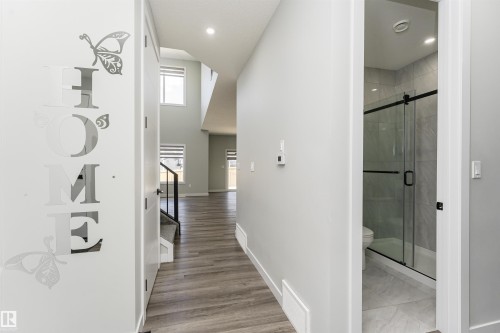 Entryway with wood-finish flooring, recessed lighting, and a prominent open staircase with dark railings - 5386 Kimball Place, Edmonton, AB - Indoor Photo Showing Other Room