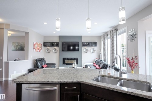 Kitchen island with granite countertop, double stainless steel sink, and integrated dishwasher - 1728 53 Street, Edmonton, AB - Indoor Photo Showing Kitchen With Double Sink