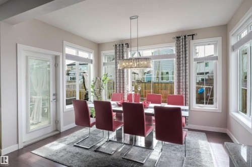 Dining area featuring wood-finish flooring, a white trim patio door, and multiple windows with white frames - 1728 53 Street, Edmonton, AB - Indoor Photo Showing Other Room