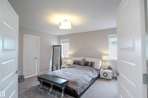Neutral-toned bedroom featuring two windows with white trim, a semi-flush mount ceiling light fixture, and plush carpeting - 1728 53 Street, Edmonton, AB - Indoor Photo Showing Bedroom