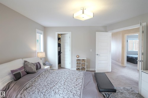Carpeted bedroom featuring soft neutral wall tones, a contemporary ceiling light fixture, a window with white trim, and a five-panel interior door - 1728 53 Street, Edmonton, AB - Indoor Photo Showing Bedroom