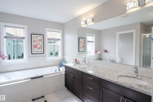 Bathroom featuring a double vanity with stone countertops, a subway tile backsplash, and dark wood cabinetry - 1728 53 Street, Edmonton, AB - Indoor Photo Showing Bathroom