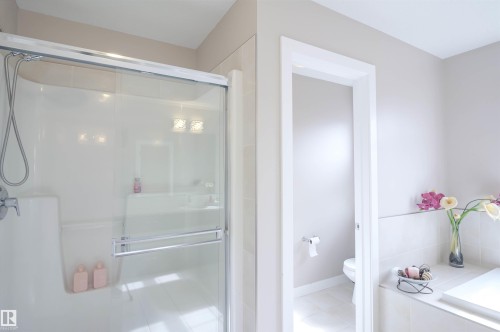 Shower enclosure with sliding glass doors, chrome hardware, and a built-in shower caddy - 1728 53 Street, Edmonton, AB - Indoor Photo Showing Bathroom
