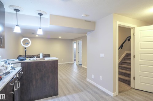 Modern lower-level space featuring wood-finish flooring, recessed lighting, and a built-in wet bar with pendant lights - 1728 53 Street, Edmonton, AB - Indoor