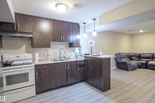Kitchenette featuring dark wood-finish cabinetry, a white electric range, and a stainless steel sink with a gooseneck faucet - 1728 53 Street, Edmonton, AB - Indoor Photo Showing Kitchen
